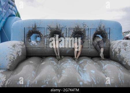 July 15, 2021-Boryeong, South Korea-A Visitors  enjoying wrestle in the mud pool during an Annual Boryeong Mud Festival at Daecheon Beach in Boryeong, South Korea. The mud, which is believed to have beneficial effects on the skin due to its mineral content, is sourced from mud flats near Boryeong and transported to the beach by truck. Stock Photo