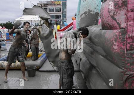 July 15, 2021-Boryeong, South Korea-A Visitors  enjoying wrestle in the mud pool during an Annual Boryeong Mud Festival at Daecheon Beach in Boryeong, South Korea. The mud, which is believed to have beneficial effects on the skin due to its mineral content, is sourced from mud flats near Boryeong and transported to the beach by truck. Stock Photo