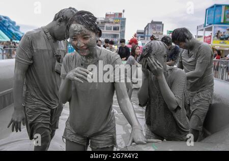 July 15, 2021-Boryeong, South Korea-A Visitors  enjoying wrestle in the mud pool during an Annual Boryeong Mud Festival at Daecheon Beach in Boryeong, South Korea. The mud, which is believed to have beneficial effects on the skin due to its mineral content, is sourced from mud flats near Boryeong and transported to the beach by truck. Stock Photo