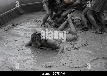 July 15, 2021-Boryeong, South Korea-A Visitors  enjoying wrestle in the mud pool during an Annual Boryeong Mud Festival at Daecheon Beach in Boryeong, South Korea. The mud, which is believed to have beneficial effects on the skin due to its mineral content, is sourced from mud flats near Boryeong and transported to the beach by truck. Stock Photo