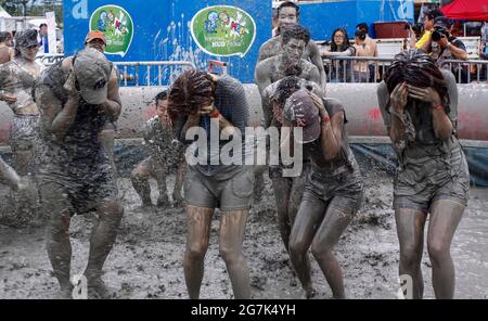 July 15, 2021-Boryeong, South Korea-A Visitors  enjoying wrestle in the mud pool during an Annual Boryeong Mud Festival at Daecheon Beach in Boryeong, South Korea. The mud, which is believed to have beneficial effects on the skin due to its mineral content, is sourced from mud flats near Boryeong and transported to the beach by truck. Stock Photo