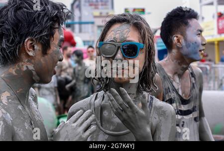 July 15, 2021-Boryeong, South Korea-A Visitors  enjoying wrestle in the mud pool during an Annual Boryeong Mud Festival at Daecheon Beach in Boryeong, South Korea. The mud, which is believed to have beneficial effects on the skin due to its mineral content, is sourced from mud flats near Boryeong and transported to the beach by truck. Stock Photo