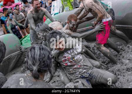 July 15, 2021-Boryeong, South Korea-A Visitors  enjoying wrestle in the mud pool during an Annual Boryeong Mud Festival at Daecheon Beach in Boryeong, South Korea. The mud, which is believed to have beneficial effects on the skin due to its mineral content, is sourced from mud flats near Boryeong and transported to the beach by truck. Stock Photo