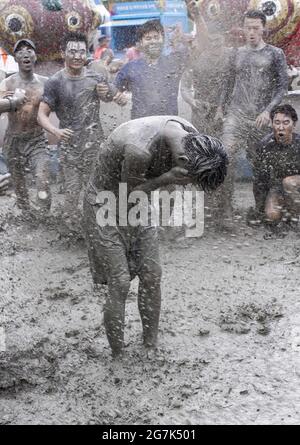 July 15, 2021-Boryeong, South Korea-A Visitors  enjoying wrestle in the mud pool during an Annual Boryeong Mud Festival at Daecheon Beach in Boryeong, South Korea. The mud, which is believed to have beneficial effects on the skin due to its mineral content, is sourced from mud flats near Boryeong and transported to the beach by truck. Stock Photo