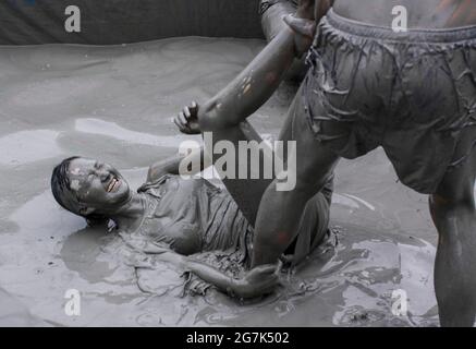 July 15, 2021-Boryeong, South Korea-A Visitors  enjoying wrestle in the mud pool during an Annual Boryeong Mud Festival at Daecheon Beach in Boryeong, South Korea. The mud, which is believed to have beneficial effects on the skin due to its mineral content, is sourced from mud flats near Boryeong and transported to the beach by truck. Stock Photo