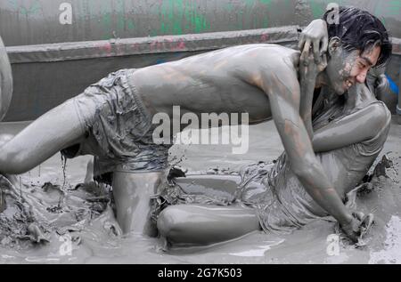 July 15, 2021-Boryeong, South Korea-A Visitors  enjoying wrestle in the mud pool during an Annual Boryeong Mud Festival at Daecheon Beach in Boryeong, South Korea. The mud, which is believed to have beneficial effects on the skin due to its mineral content, is sourced from mud flats near Boryeong and transported to the beach by truck. Stock Photo