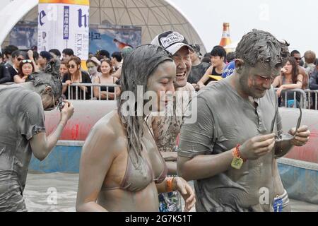 July 15, 2021-Boryeong, South Korea-A Visitors  enjoying wrestle in the mud pool during an Annual Boryeong Mud Festival at Daecheon Beach in Boryeong, South Korea. The mud, which is believed to have beneficial effects on the skin due to its mineral content, is sourced from mud flats near Boryeong and transported to the beach by truck. Stock Photo