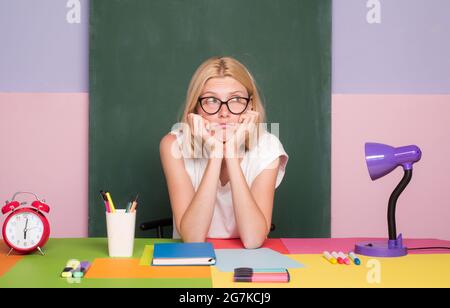 Education, school and people concept. Happy smiling young student or teacher near green chalkboard background. Deadline learning and doing homework. Stock Photo