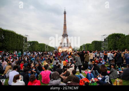 Large crowd gathered in Paris to celebrate Bastille Day 2021 in front of the Eiffel Tower - Vaccinated parisians enjoy a concert on the Champ de Mars Stock Photo