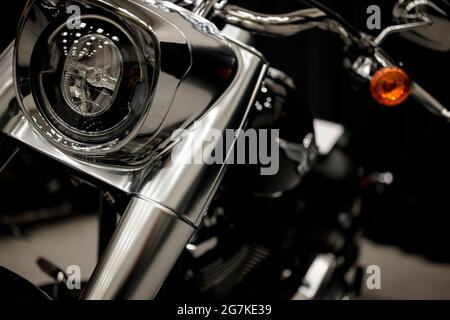 Matte chrome motorcycle with a powerful fork and stylized headlamp stands on the court in the reflection of glowing lights hiding its details in shade Stock Photo