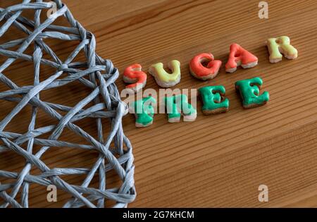 Sugar free cookies cut in the shape of letters saying a text in english with colorful dip on a wooden surface with texture Stock Photo