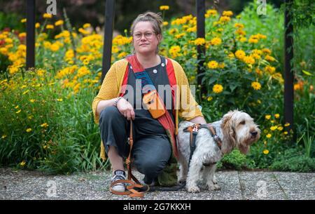 Hameln, Germany. 14th July, 2021. Katja Gleisberg squats with her dog Frida in Bürgerpark. The 42-year-old from Hamelin experienced sexualised violence in her childhood and reported her stepfather in 2013 - 20 years after the experience. Victims like Katja Gleisberg demand protection concepts for children. (to dpa 'Tatort Familie: Betroffene fordern Schutzkonzepte für Kinder') Credit: Julian Stratenschulte/dpa/Alamy Live News Stock Photo