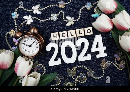 Hello 2024 alphabet letter decorate with alarm clock on blue knitted fabric background. Stock Photo