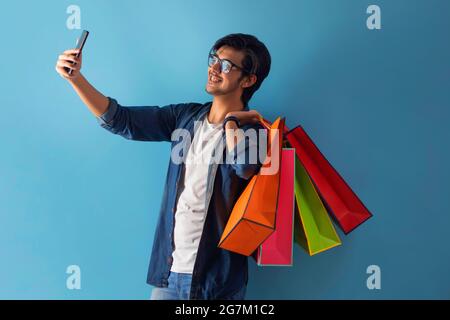 A young man clicking a selfie with Carry bags. Stock Photo