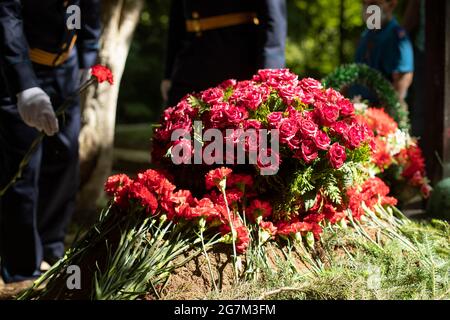 Flowers on the grave. Funeral ceremony. Flowers lie on the ground. Filled grave. Stock Photo