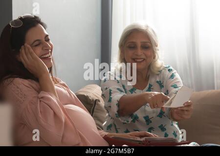 A PREGNANT WOMAN AND MOTHER REMEMBERING HAPPY OLD DAYS BY LOOKING AT PHOTOGRAPHS Stock Photo