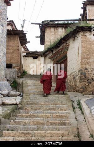 Monks climbing up a stone staircase in the streets in Shangri-La, China Stock Photo