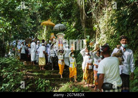 GIANYAR,BALI-MAY 11 2021: Balinese Hindu community is holding a cleansing ceremony to the forest and river in Ubud. They bring offerings and wear medi Stock Photo
