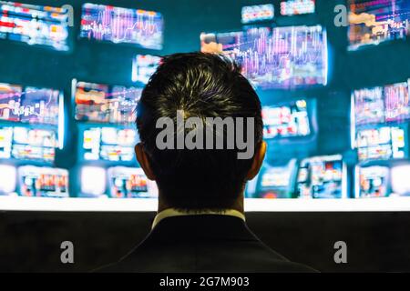Back view of businessman trader looking at monitor with stock exchange graph. Stock Photo