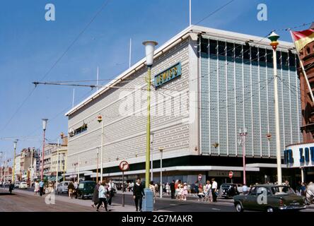 Lewis’s department store on the promenade, Blackpool, Lancashire, England, UK c. 1968. Lewis's was a chain of British department stores that operated from 1856 to 2010. The first store, which opened in Liverpool city centre, became the flagship of the chain of stores operating under the Lewis's banner. The modern Blackpool branch stood next to Blackpool Tower and was opened in 1964 on the site of the old Alhambra. It closed in 1993 and the building was stripped back before being reclad in brick. This image is from an old amateur 35mm colour transparency – a vintage 1960s photograph. Stock Photo