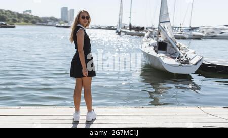 Woman in dress enjoys sea on the pier. Stock Photo