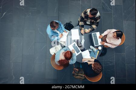 Top view of group of students sitting together at table. university students doing group study. Stock Photo