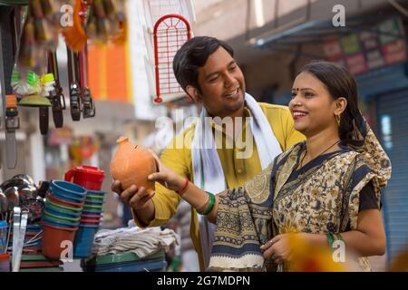 A RURAL HUSBAND HAPPILY LOOKING AT WIFE WHILE HOLDING PIGGY BANK Stock Photo