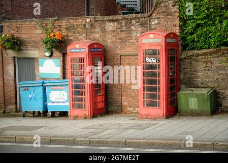 A pair of old faded red telephone boxes in Exeter, Devon. Stock Photo
