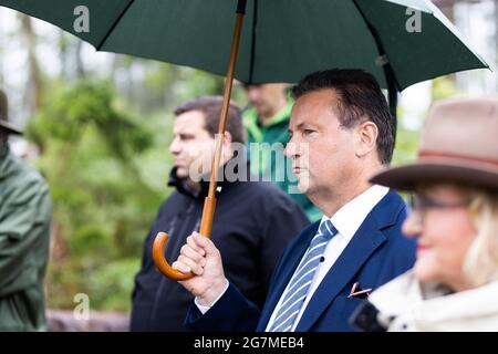 Albbruck, Germany. 15th July, 2021. State Minister Peter Hauk (CDU, with umbrella) stands in the forest during an inspection. The southern Black Forest is one of the regions in Baden-Württemberg most affected by extreme weather-related forest damage. In order to develop solutions, the forest was declared a model area. The aim of the project is to support and quickly help forest owners both in dealing with the damage and in reforesting the damaged areas. Credit: Philipp von Ditfurth/dpa/Alamy Live News Stock Photo
