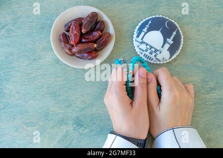 Concept of muslim.top view of female hands holding rosary near dates and gingerbread with mosque. Muslim woman in white clothes holds a rosary. Flat lay. copy space. Ramadan Kareem background. Stock Photo