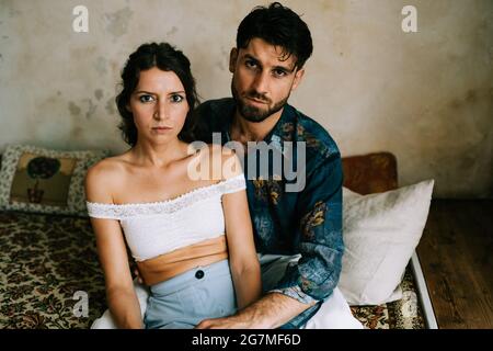 serious heterosexual couple sitting on sofa Stock Photo