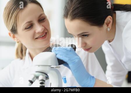 Female scientists chemists looking through microscope in laboratory Stock Photo