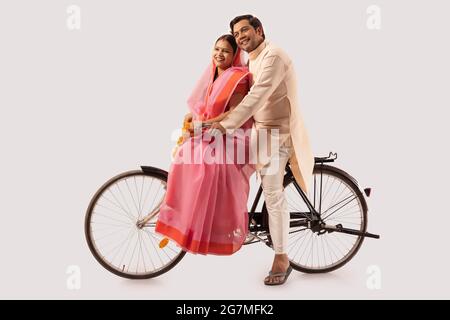 A RURAL COUPLE SITTING TOGETHER ON NEW BICYCLE AND HAPPILY LOOKING AWAY Stock Photo