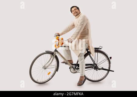 A RURAL MAN HAPPILY POSING WHILE SITTING ON NEW BICYCLE Stock Photo