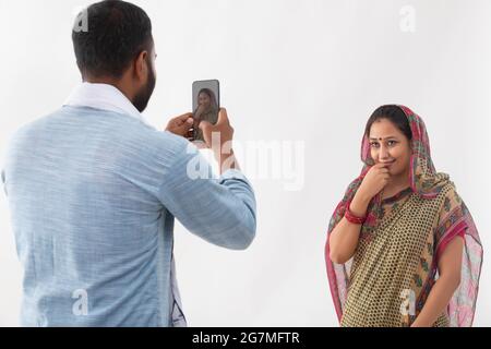 PORTRAIT OF A RURAL HUSBAND AND WIFE CLICKING SELFIE IN MOBILE Stock