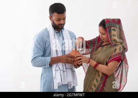 PORTRAIT OF A RURAL MAN AND WOMAN SAVING MONEY IN A PIGGY BANK Stock Photo