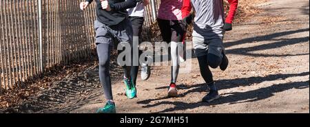A small group of high school cross country runners running together on a dirt path uphill at Sunken Meadow State Park. Stock Photo