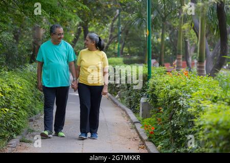 A SENIOR COUPLE WALKING HAND IN HAND IN A PARK Stock Photo