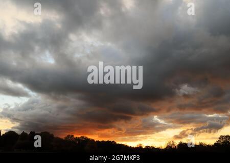 Cloudscape at sunset in the Ouse Valley with orange and yellow colours beneath stormy grey clouds - Bedfordshire, England, UK Stock Photo