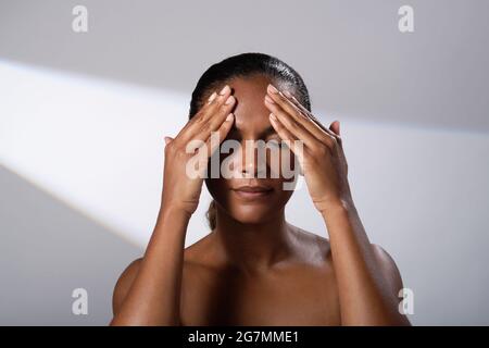 Beauty images of a woman with darker skin tone. Head and shoulder pictures of smiling, happy lady. Face massage/cream application. Stock Photo