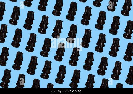 Black, dark knight chess piece multiplied on soft, trendy pastel blue background. Minimal games and recreation concept. Stock Photo