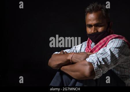 A LABOURER WEARING FACE MASK SITTING ALONE Stock Photo