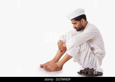 A COMMON MAN SITTING DOWN AND SADLY THINKING Stock Photo