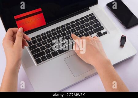 Human hand operating laptop with a card in another hand. Stock Photo