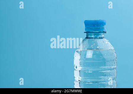 Water bottle on blue. Transparent plastic bottle with cap with drops Stock Photo