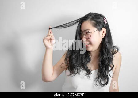 Asian Shy girl happy and smile with playing her hair in studio light white background. Stock Photo