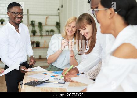 Happy smiling team of multinational people laugh, smile and rejoice at the victory, the signed contract or the signed agreement. Stock Photo