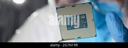 Researcher holds small microcircuit with tongs closeup Stock Photo