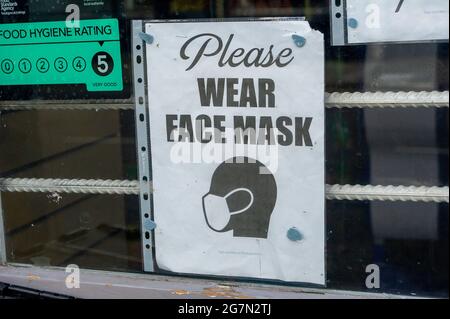 Eton, Windsor, Berkshire, UK. 14th July, 2021. A Covid-19 face mask notice in a shop window in Eton High Street. Following the announcement by Boris Johnson that the Covid-19 lockdown is ending in England from Monday 19th July, 2021, over a thousand scientists and doctors are reported to be very concerned about people no longer having to legally adhere to Covid-19 prevention measures. Credit: Maureen McLean/Alamy Stock Photo