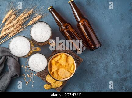 Beer, chips and wheat spikelets on a dark blue background. Stock Photo